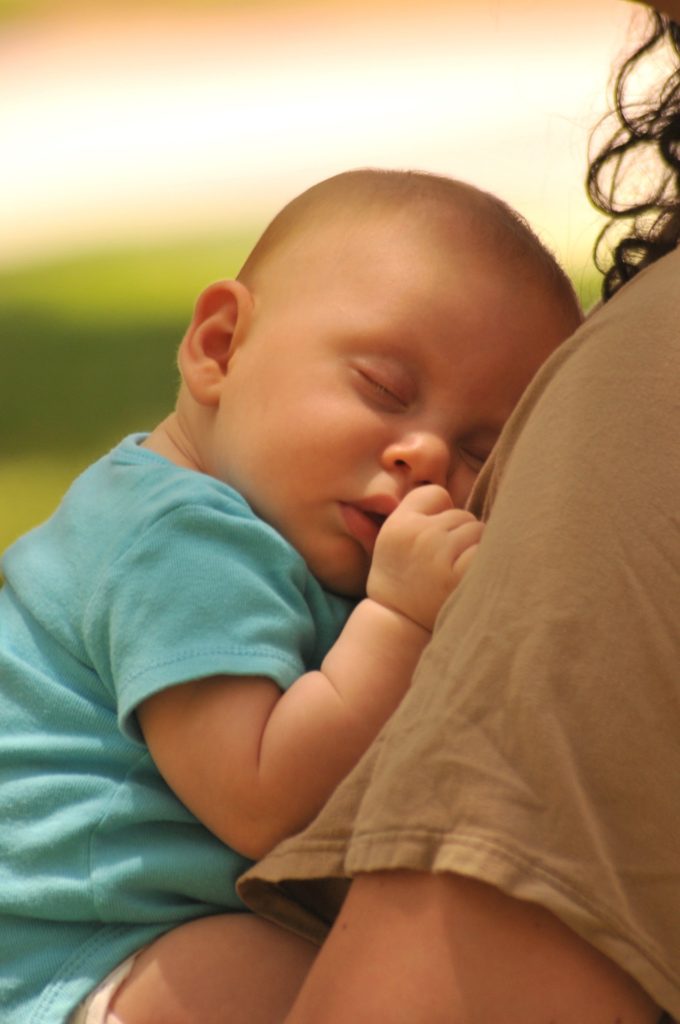 un bébé endormi dans les bras de sa mama, sans stress ni angoisse