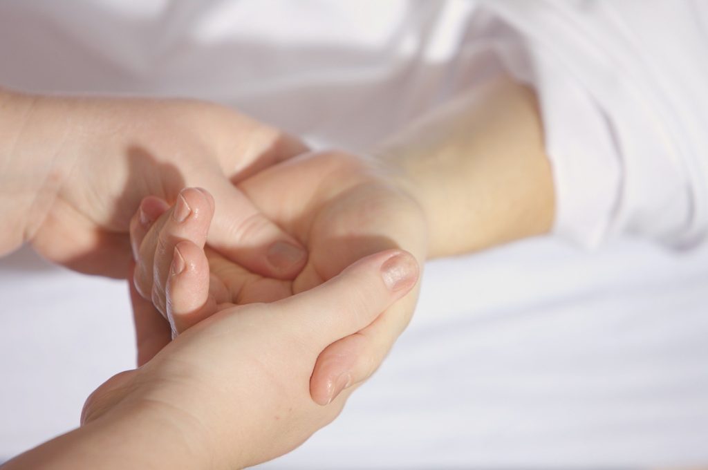 Une main adulte palpe la paume d'une main d'enfant, recherchant un effet anti-stress