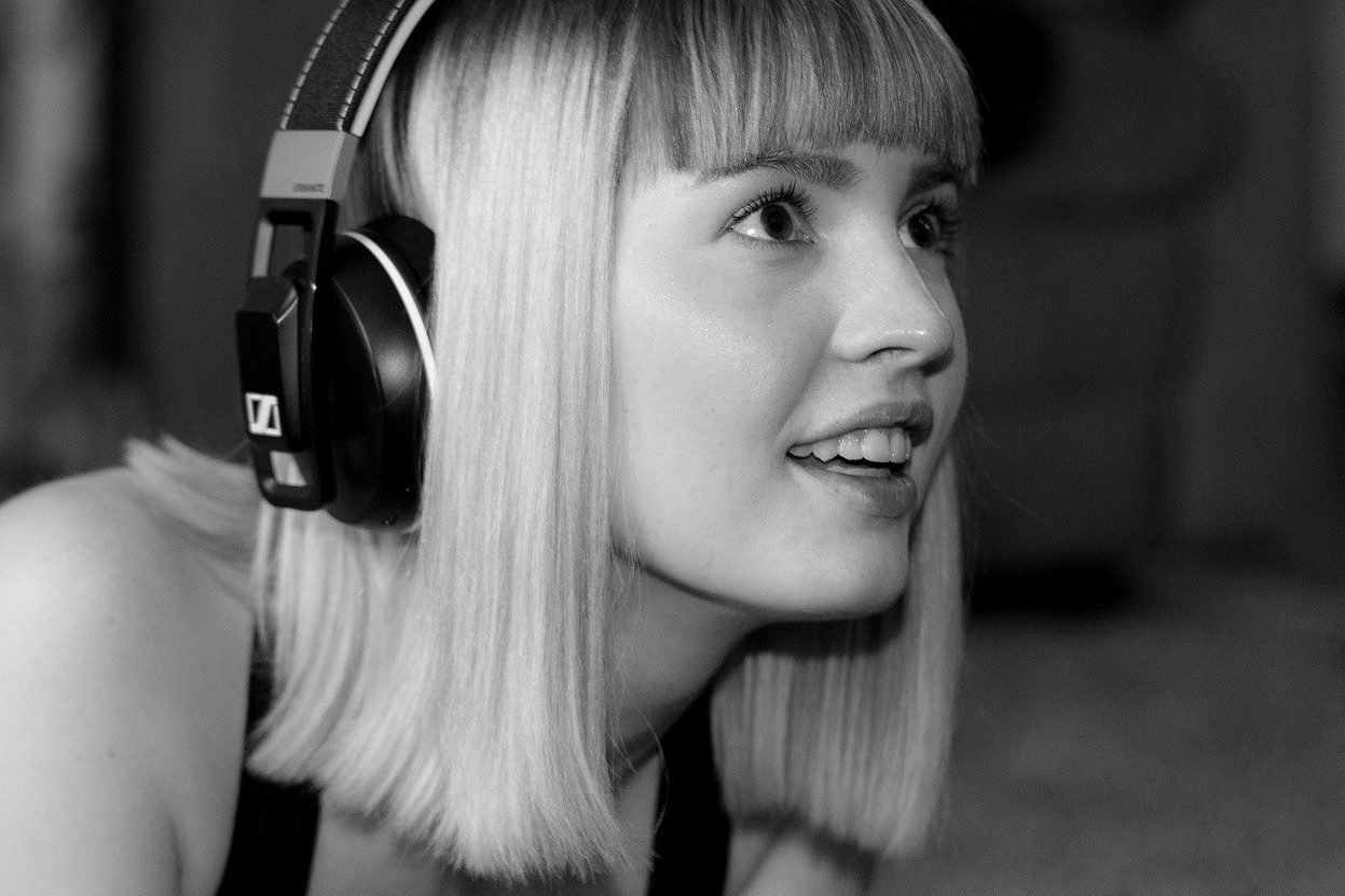 en noir et blanc, une jeune fille portant un casque audio sourit de plaisir en écoutant sa musique anti stress