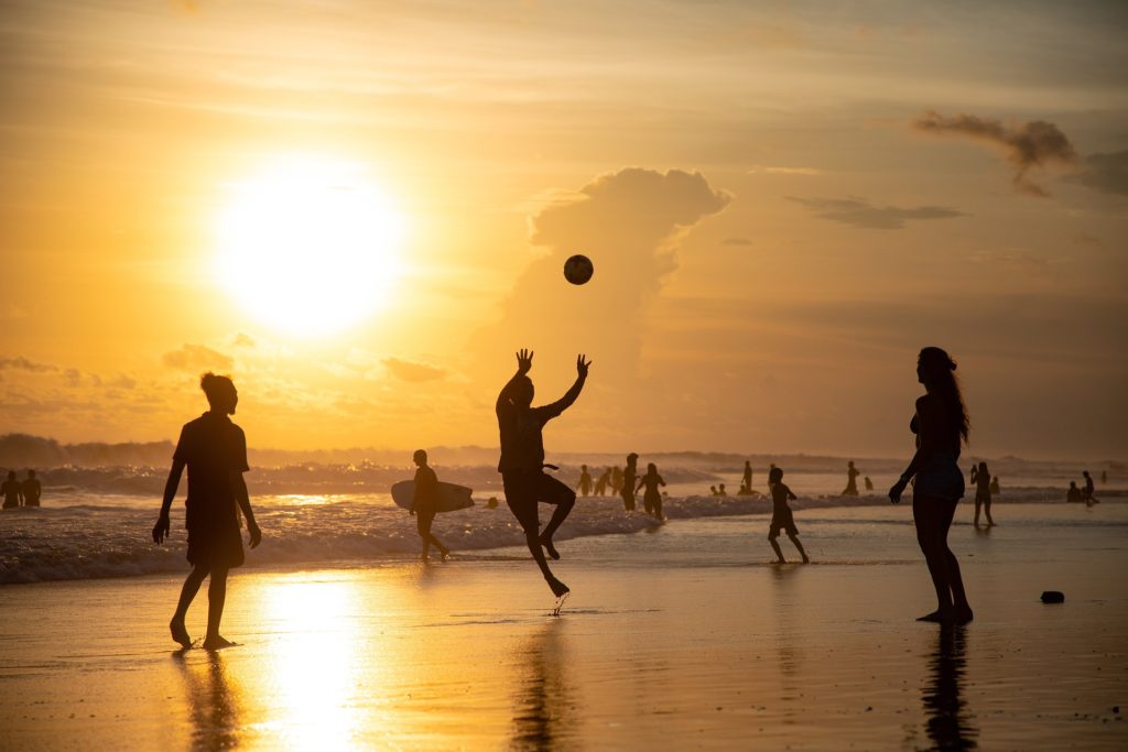 des joueurs de volley sur une plage au coucher de soleil : le sport améliore l'hygiène de vie et la bonne santé