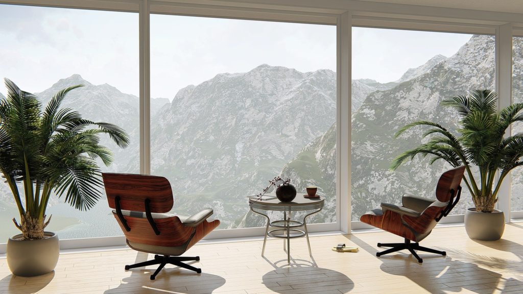 2 fauteuils design, un guéridon les sépare, face à une baie vitrée derrière laquelle on contemple une paisible chaine de montagne rocheuses