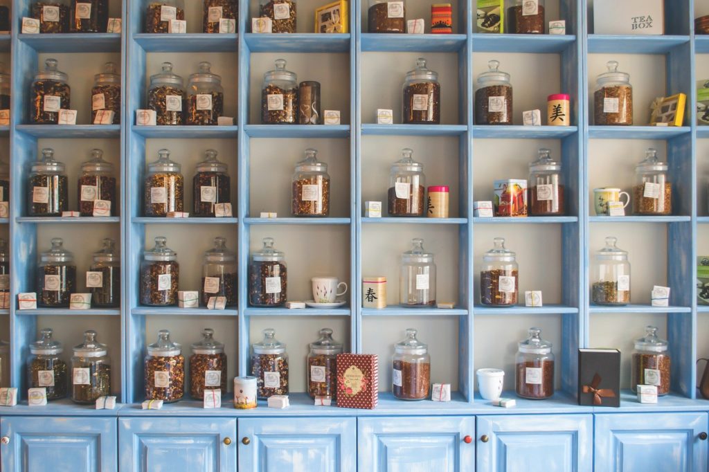 des étagères de bois, rappelant une pharmacie ancienne, comporte dans chacune de ses cases des bocaux de verres, remplis de plantes médicinales et de compléments alimentaires qui semblent naturels.
